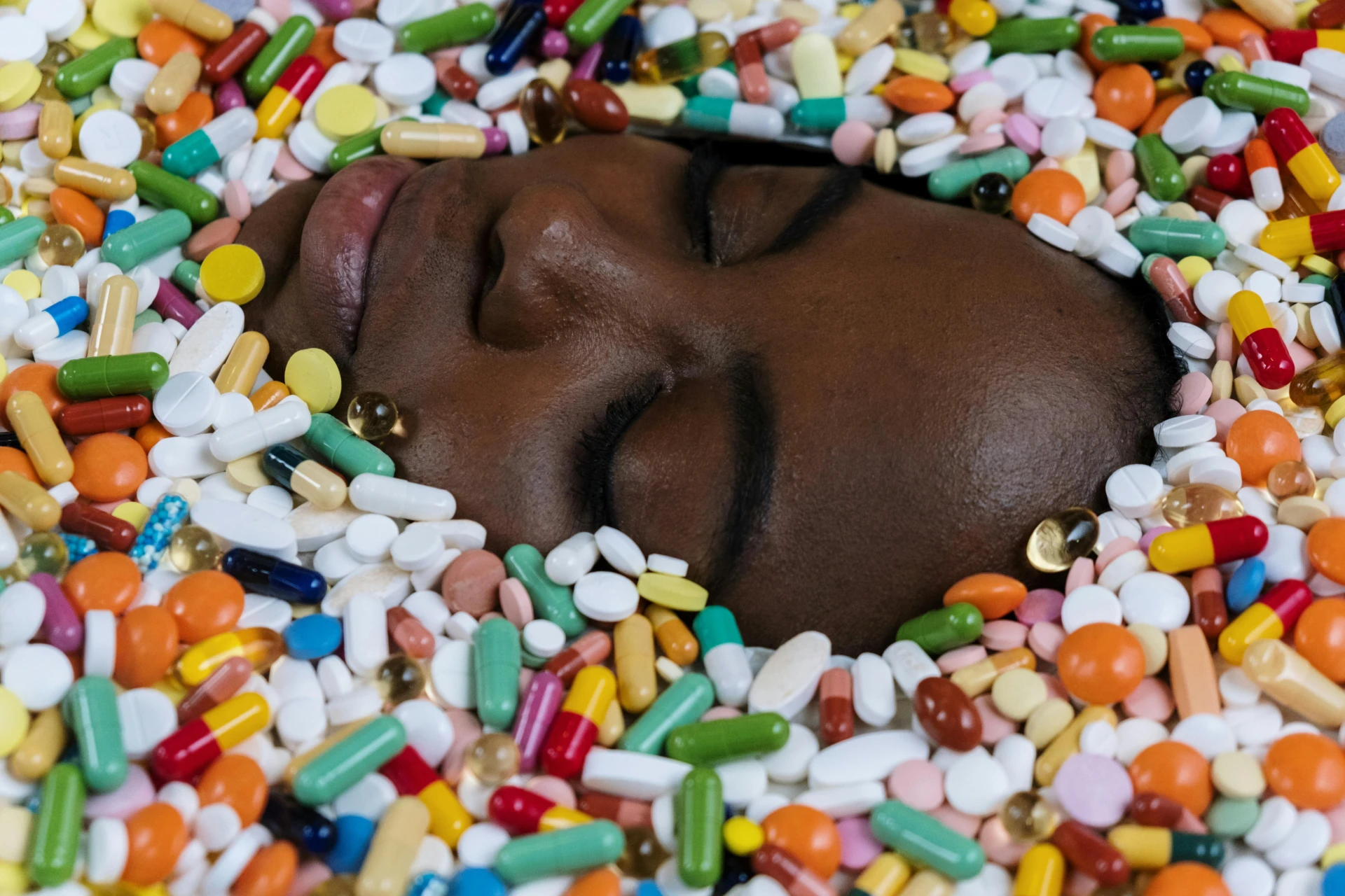A woman peacefully sleeping with only her face visible, surrounded by various types of sleeping pills scattered around her. : Strongest Sleep Aid Over the Counter