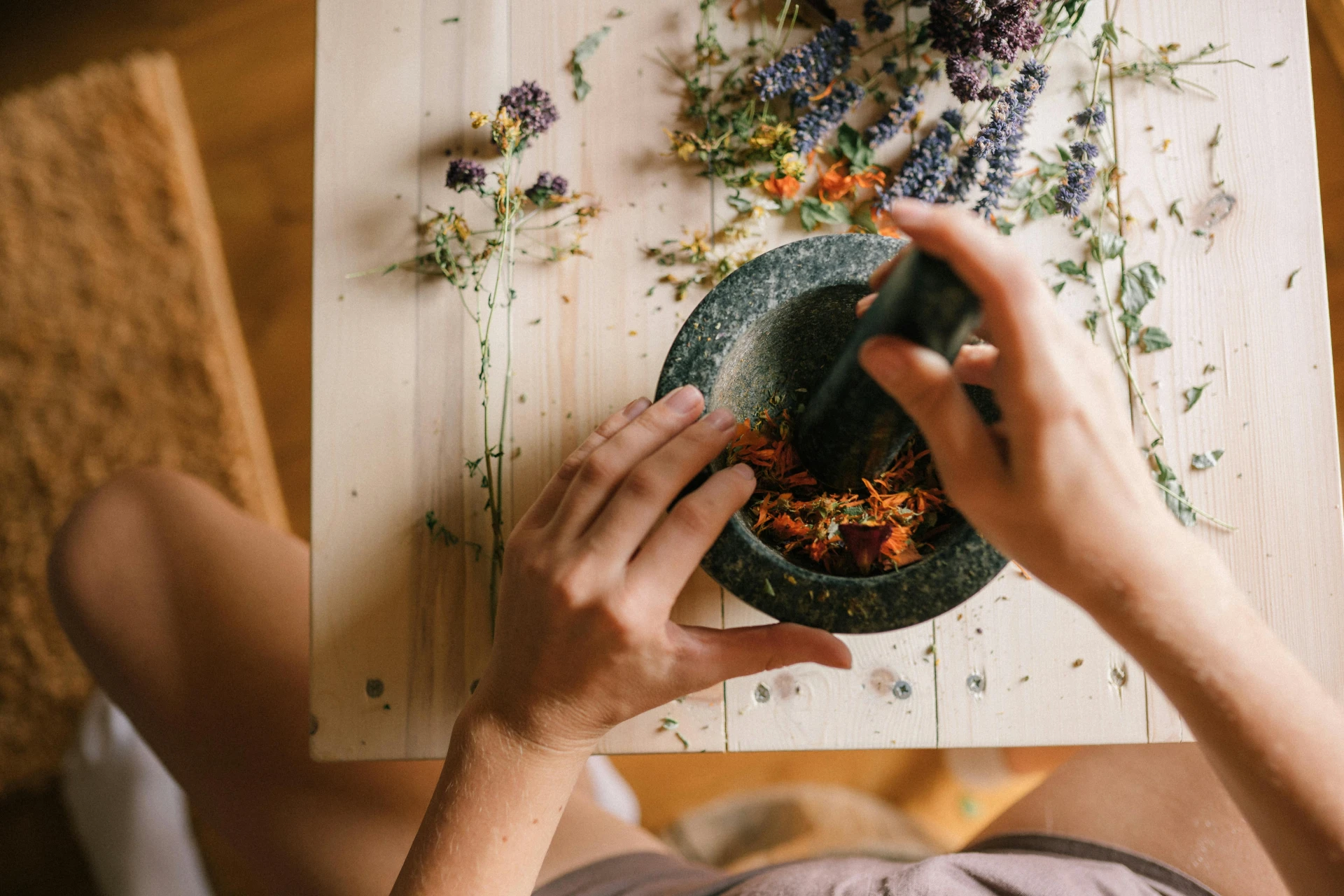 A hand grinding herbs with a mortar and pestle : Adaptogenic Herb Sleep Supplements
