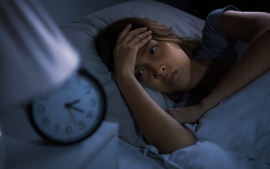 woman in her bed watching the clock and trying to sleep