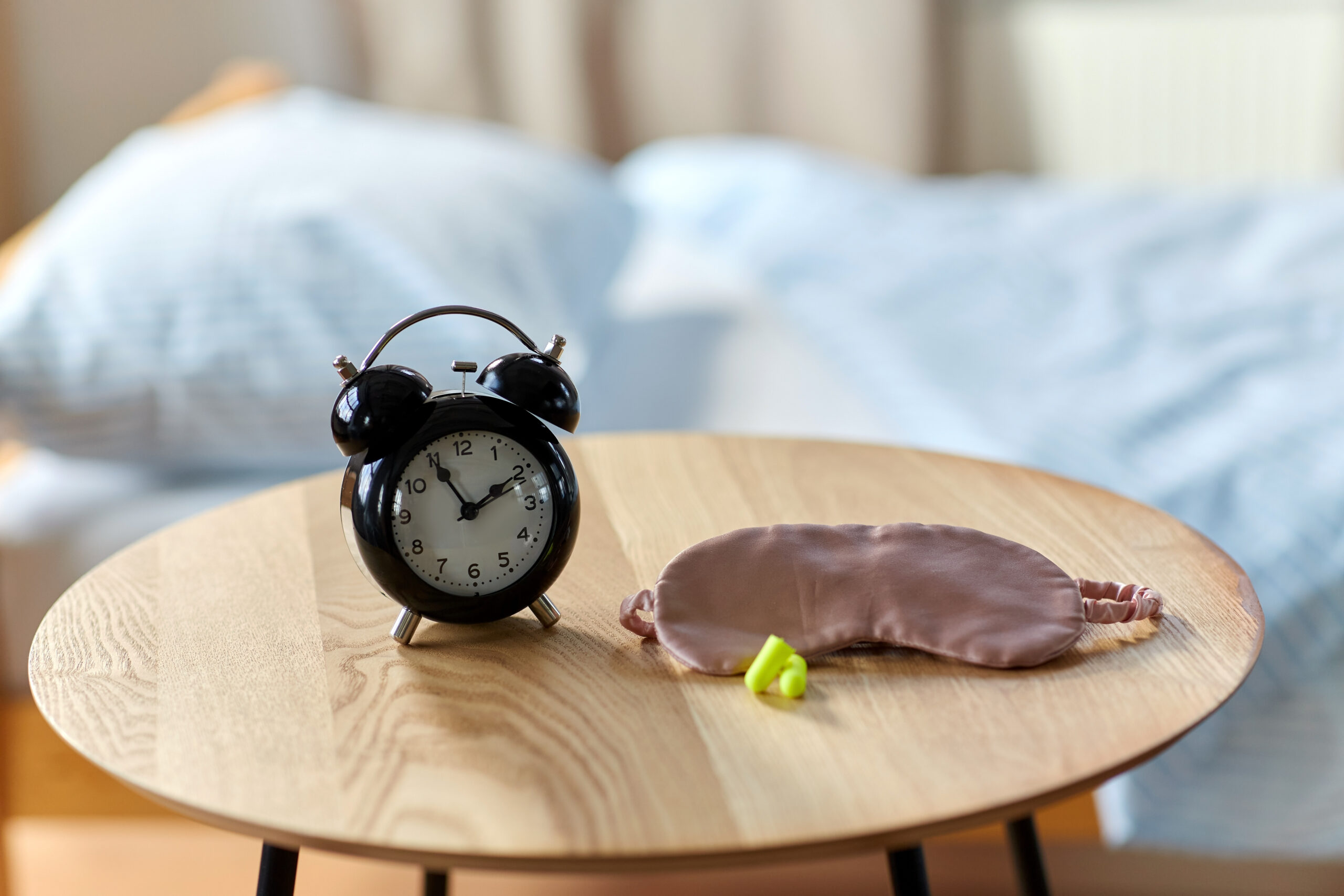 alarm clock, earplugs and sleeping mask on table clock on the table with a sleep mask
