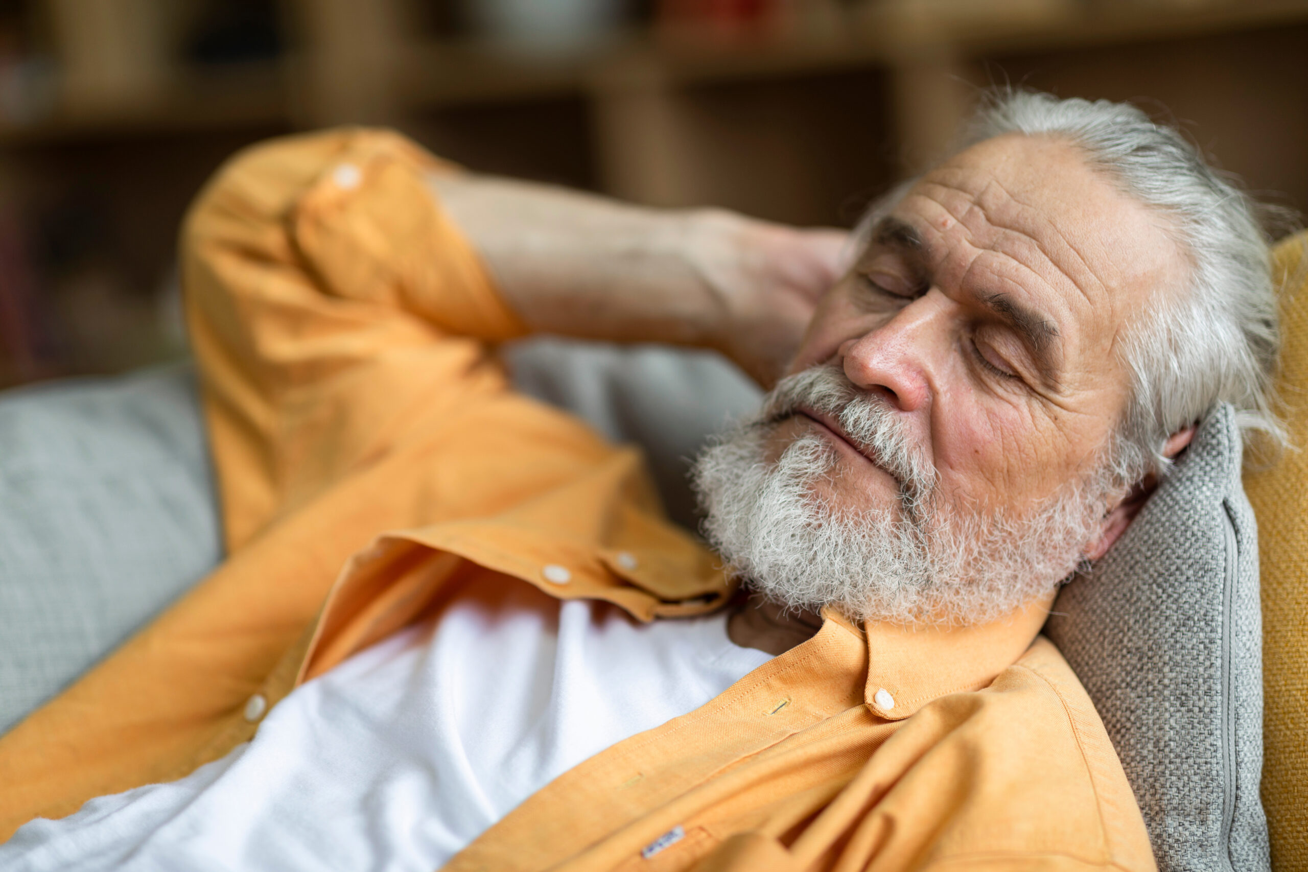 Closeup of sleeping senior man, resting on sofa at home grandfather sleeping at home in the living room