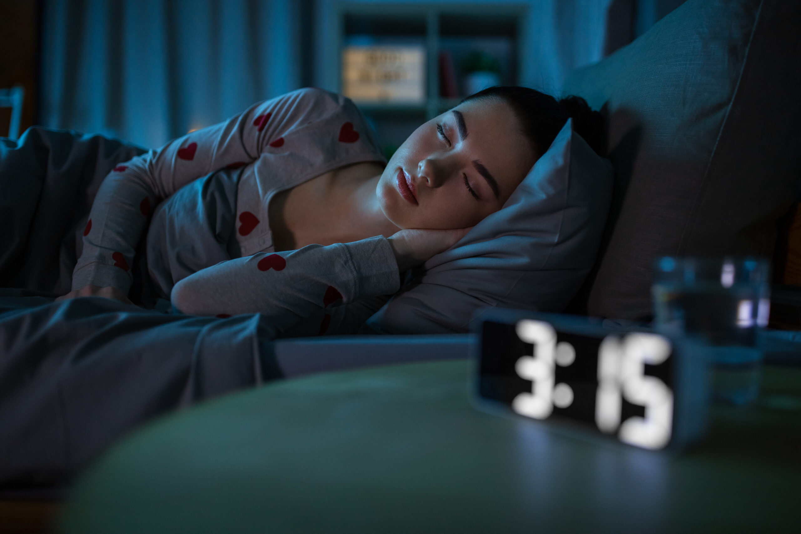 teenage girl sleeping at home at night The view of a woman sleeping soundly in her room in her bed with an alarm clock beside her